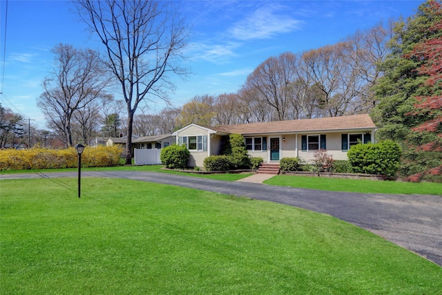 ranch-style house with aphalt driveway, roof with shingles, and a front yard