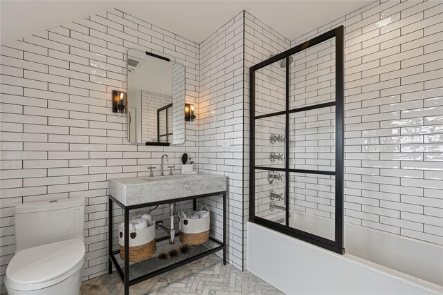 2 Fargo Ln, Irvington, NY 10533 - bathroom with tile walls, bath / shower combo with glass door, a sink, and toilet