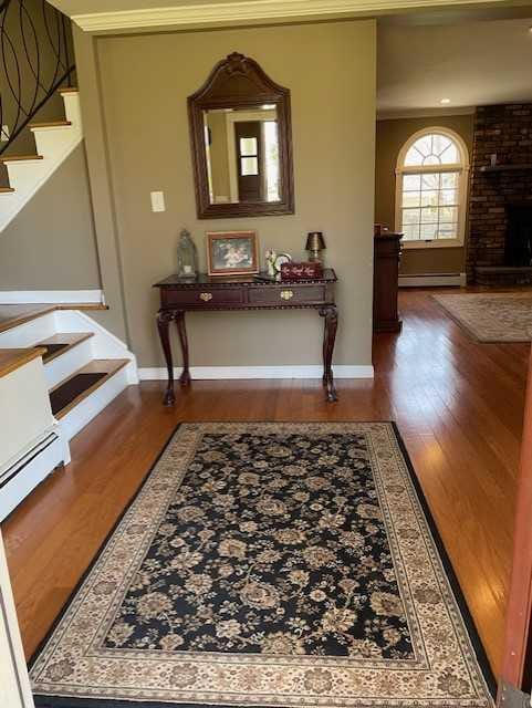 corridor featuring baseboards, a baseboard radiator, stairs, and wood finished floors