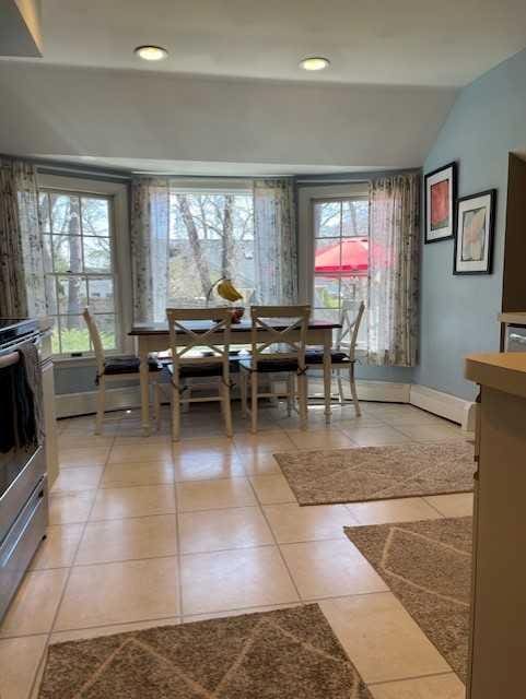 dining area featuring baseboards, vaulted ceiling, and light tile patterned floors