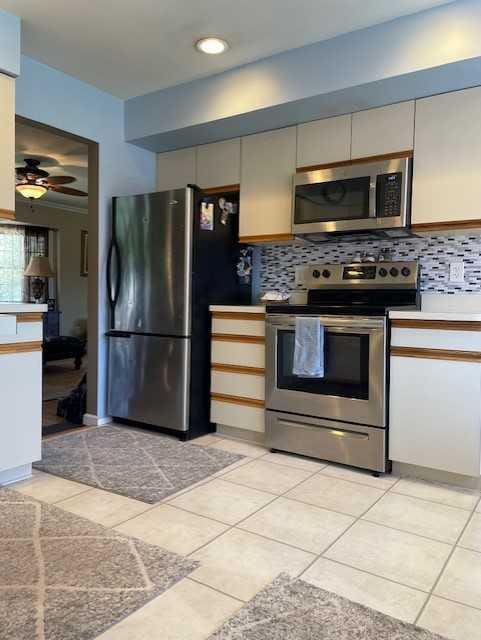 kitchen with light tile patterned floors, light countertops, decorative backsplash, and stainless steel appliances