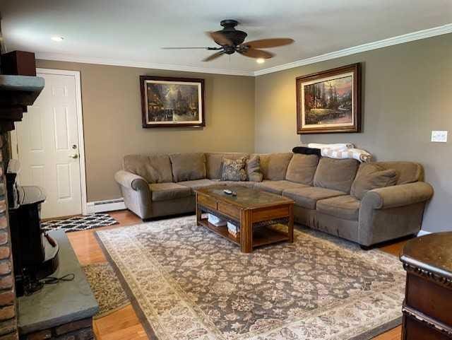 living room featuring crown molding, ceiling fan, baseboards, wood finished floors, and a baseboard radiator
