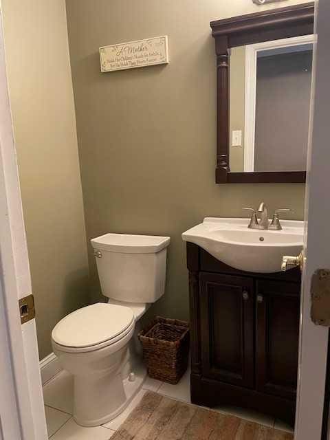 half bath with tile patterned flooring, toilet, and vanity