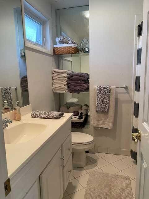 bathroom with toilet, tile patterned floors, and vanity