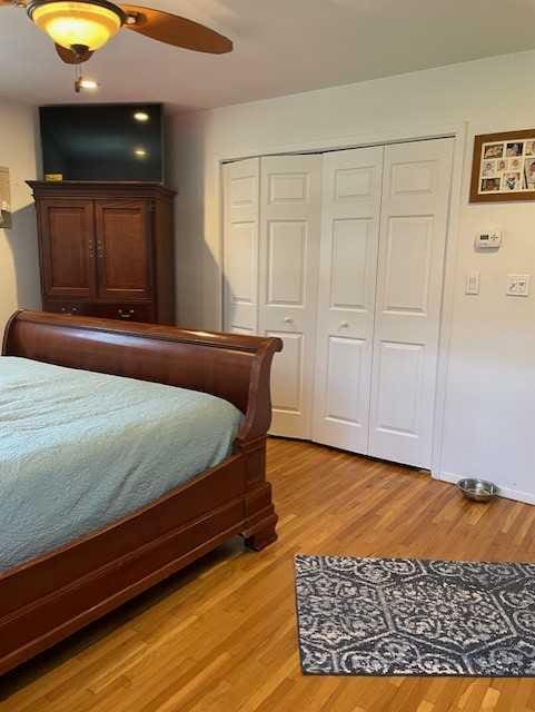 bedroom with a ceiling fan, light wood-style floors, and a closet