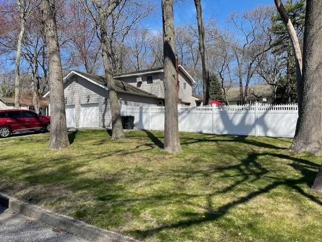 view of home's exterior with a lawn, a garage, and fence