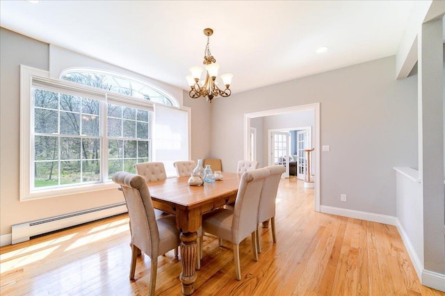 dining space with a baseboard heating unit, a healthy amount of sunlight, an inviting chandelier, and light wood-type flooring