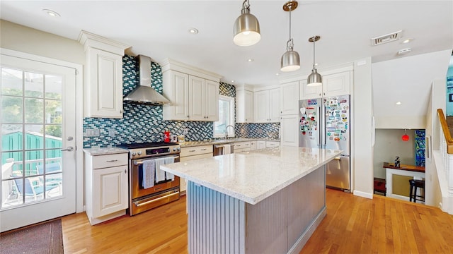 3359 Knight St, Oceanside, NY 11572 - kitchen with wall chimney range hood, backsplash, visible vents, light wood finished floors, and stainless steel appliances