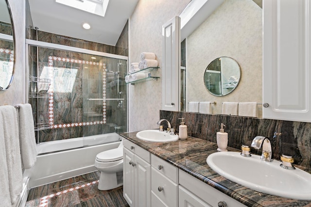 bathroom with shower / bath combination with glass door, a skylight, toilet, and a sink