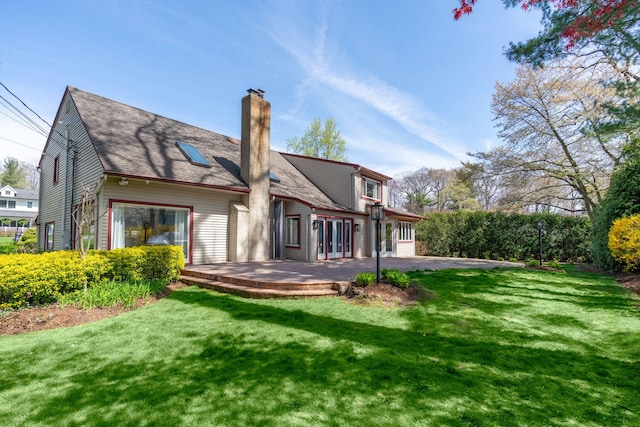 rear view of house with a chimney, a patio area, and a yard