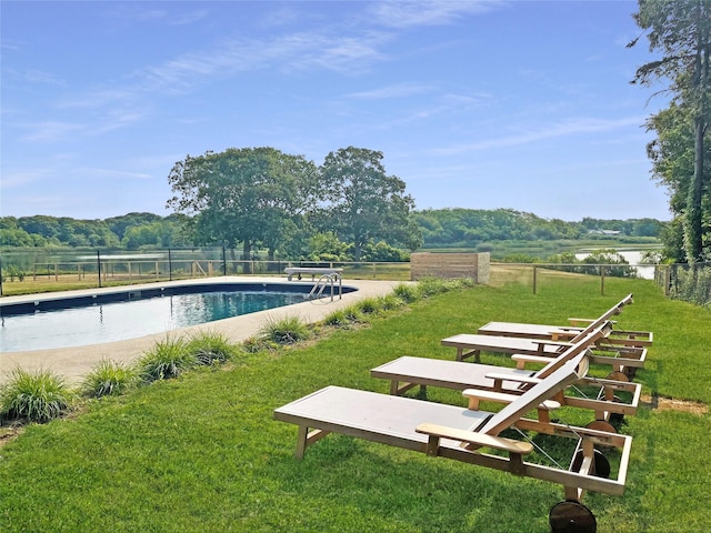 pool featuring fence, a water view, and a yard