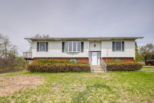 raised ranch featuring entry steps and a front lawn
