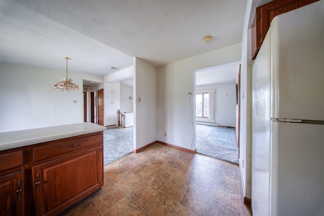 kitchen with an inviting chandelier, freestanding refrigerator, baseboards, baseboard heating, and light countertops