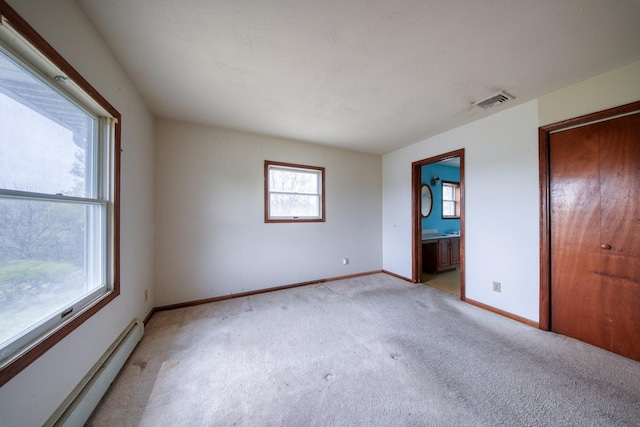 unfurnished bedroom with light colored carpet, baseboards, baseboard heating, and visible vents
