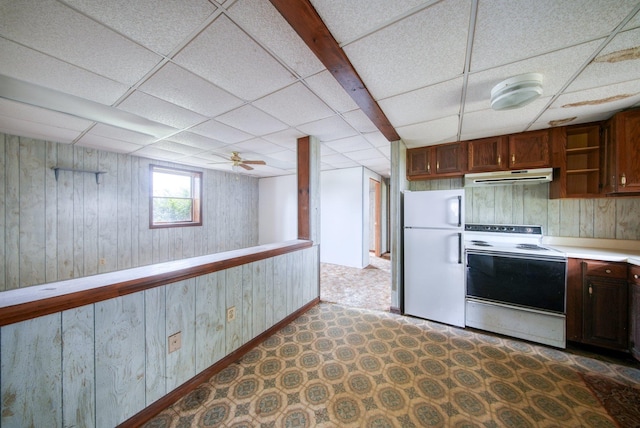 kitchen featuring wood walls, white appliances, a drop ceiling, light countertops, and under cabinet range hood