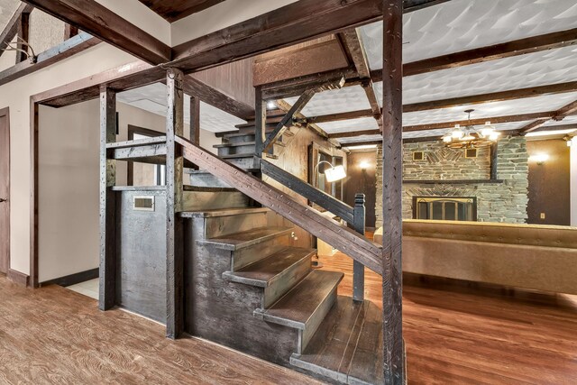 85 Woodard Rd, Parksville, NY 12768 - staircase featuring wood finished floors, a fireplace, beam ceiling, baseboards, and a chandelier