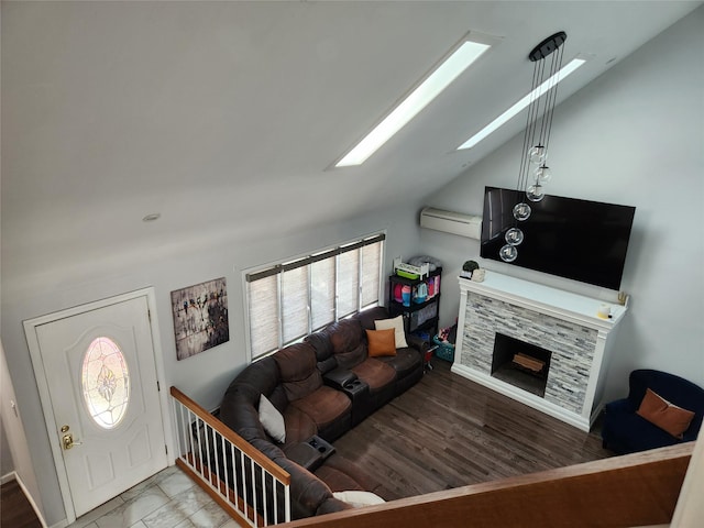 living area with a stone fireplace, lofted ceiling with skylight, and a wall mounted AC