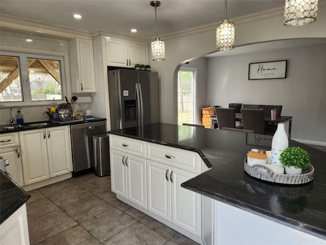 kitchen featuring arched walkways, dark countertops, stainless steel appliances, and a sink