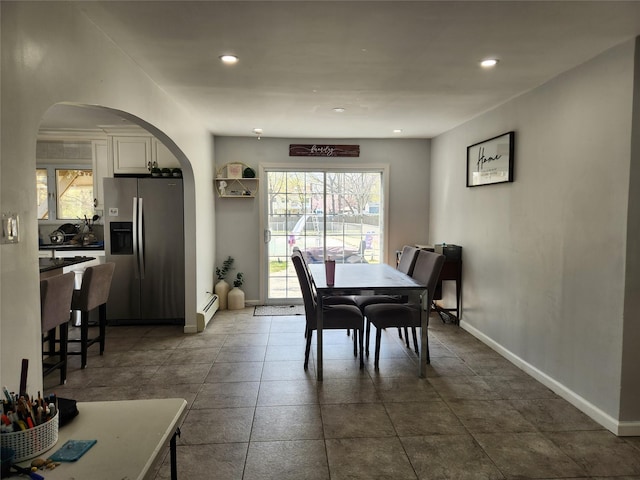 dining room featuring baseboard heating, baseboards, arched walkways, and recessed lighting