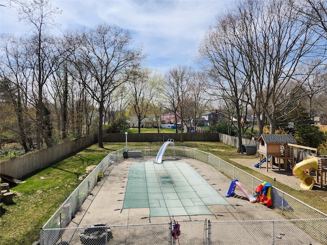 view of pool featuring a fenced in pool, a fenced backyard, playground community, a water slide, and a lawn