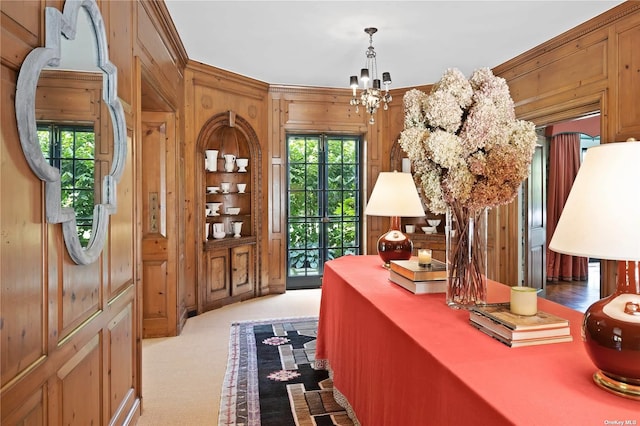foyer with wood walls, an inviting chandelier, and light carpet