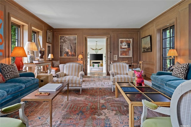 living area featuring wooden walls, ornamental molding, and a decorative wall