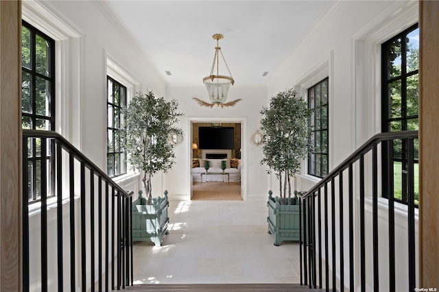 interior space with crown molding, a notable chandelier, tile patterned flooring, a fireplace, and baseboards