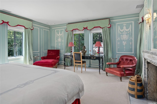 carpeted bedroom featuring a fireplace, visible vents, and a decorative wall