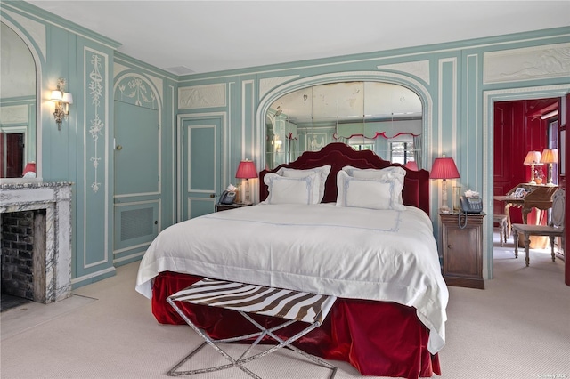 carpeted bedroom with a fireplace with flush hearth and a decorative wall
