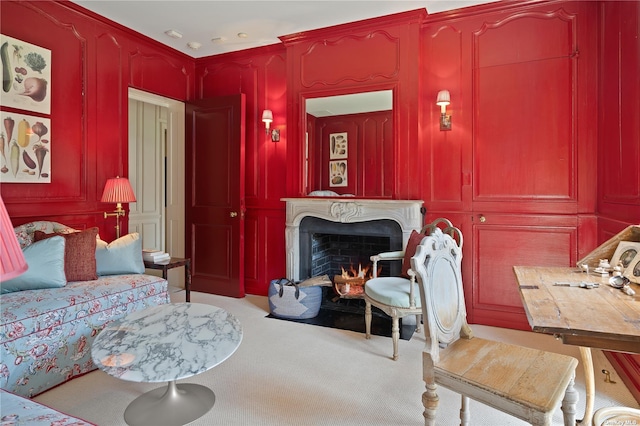 living area with light carpet, a decorative wall, and a premium fireplace