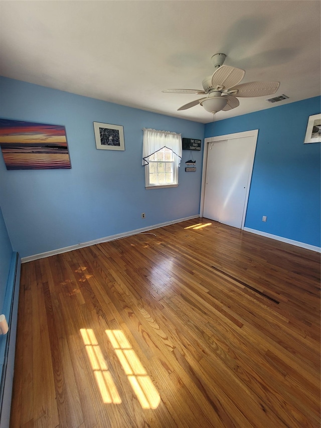 unfurnished room with ceiling fan, baseboards, wood finished floors, and visible vents