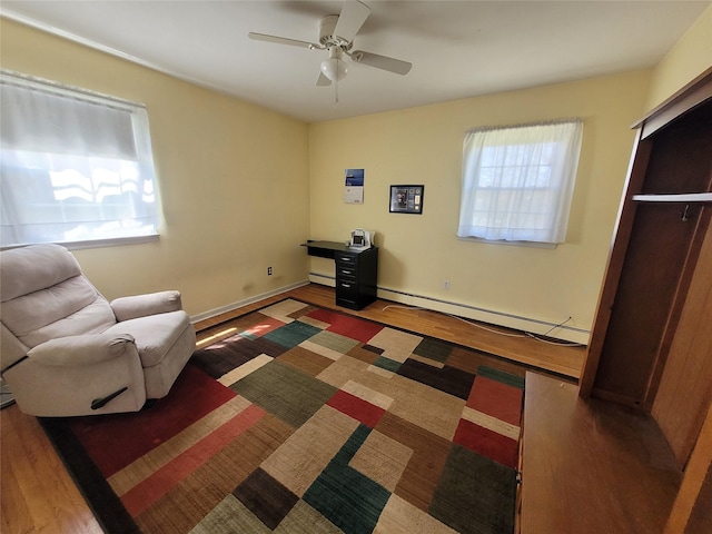 bedroom with a baseboard radiator, baseboards, a ceiling fan, and wood finished floors