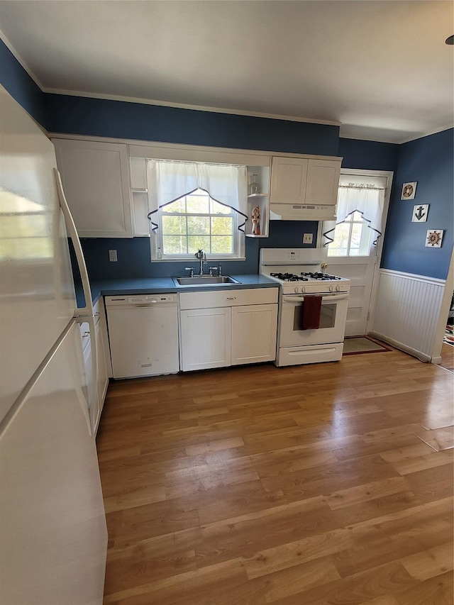 kitchen with white cabinets, light wood-style flooring, white appliances, and a sink