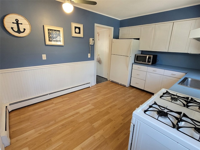 kitchen with light wood-style flooring, a wainscoted wall, white cabinetry, white appliances, and a baseboard radiator