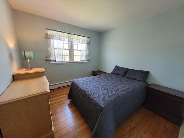 bedroom with a baseboard radiator and wood finished floors
