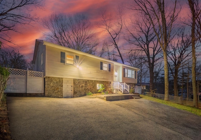 bi-level home with fence and stone siding