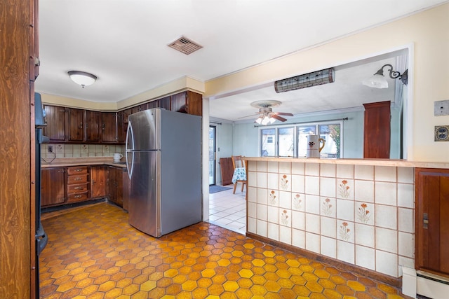 kitchen featuring visible vents, ceiling fan, light countertops, baseboard heating, and freestanding refrigerator