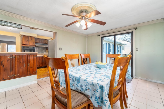 dining room featuring crown molding, light tile patterned flooring, a ceiling fan, and baseboards