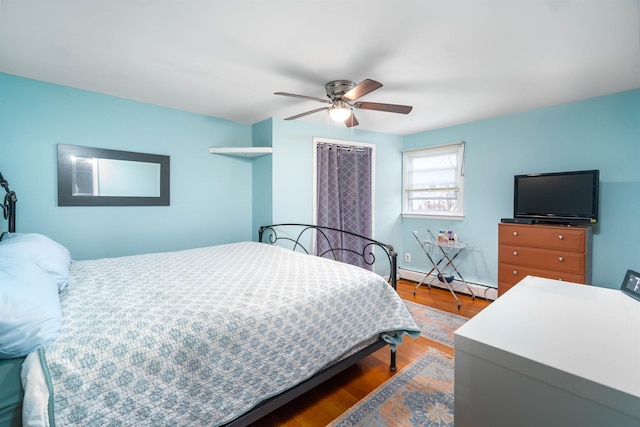 bedroom featuring ceiling fan, baseboard heating, and wood finished floors