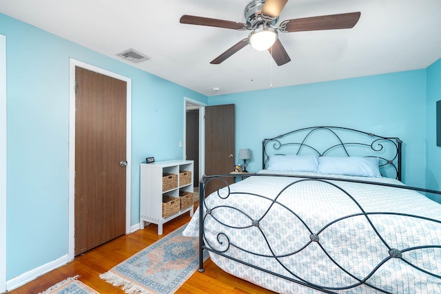 bedroom featuring wood finished floors, visible vents, a ceiling fan, and baseboards