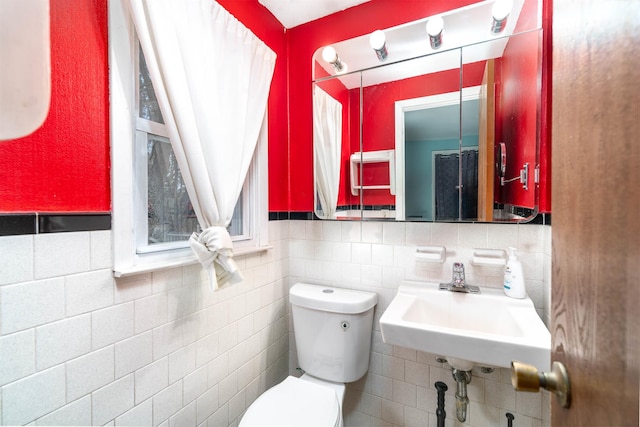 bathroom with toilet, tile walls, a sink, and tasteful backsplash