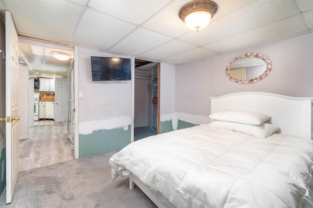 bedroom featuring a paneled ceiling, light carpet, and a closet