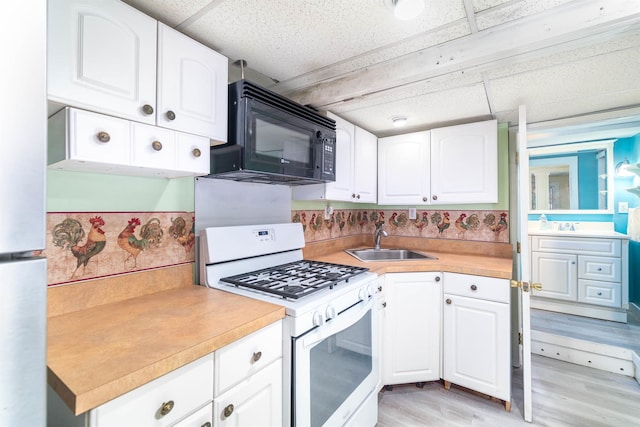 kitchen with light wood-style floors, light countertops, white gas range, a sink, and black microwave