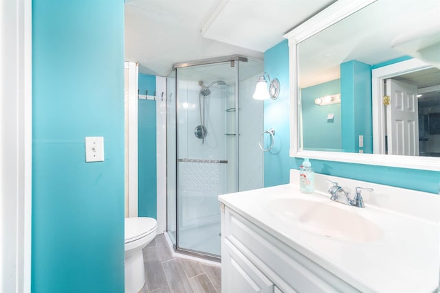 bathroom with toilet, a shower stall, and vanity
