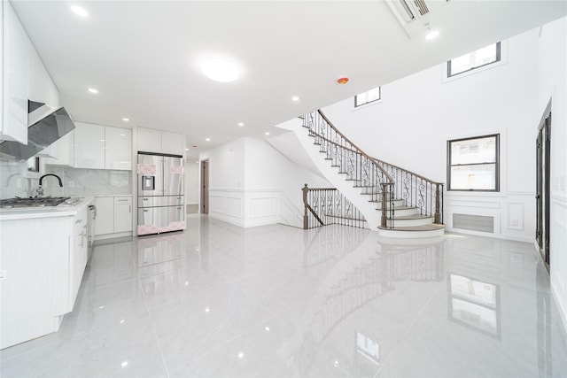 3405 Corporal Kennedy St, Bayside, NY 11361 - unfurnished living room with stairs, a decorative wall, recessed lighting, a wainscoted wall, and light tile patterned floors