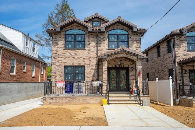 3405 Corporal Kennedy St, Bayside, NY 11361 - traditional-style home featuring brick siding, fence, french doors, and a tile roof