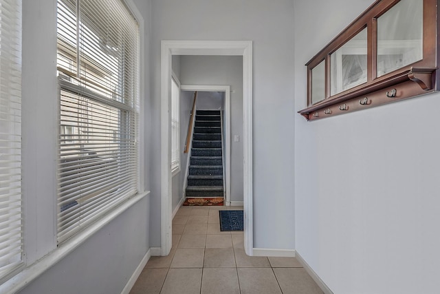 hall with a wealth of natural light, baseboards, and light tile patterned floors