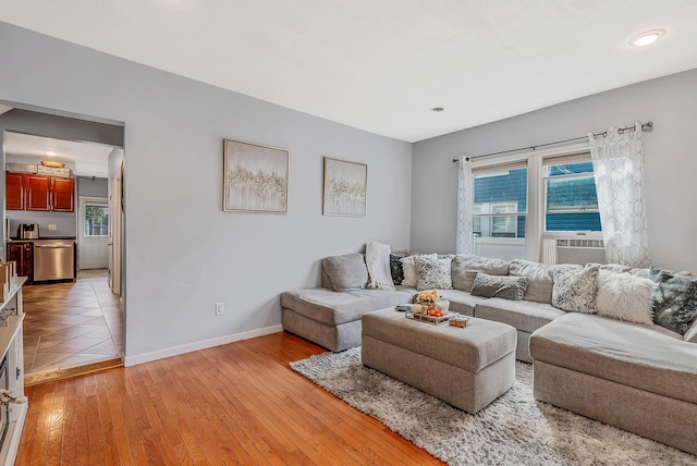 living room featuring baseboards, light wood-style flooring, cooling unit, and plenty of natural light
