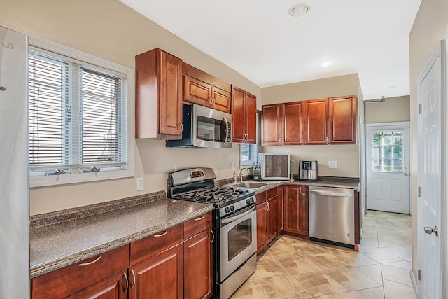 kitchen featuring a sink, dark countertops, recessed lighting, appliances with stainless steel finishes, and light tile patterned floors