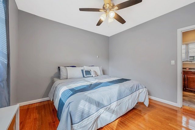 bedroom with light wood finished floors, a ceiling fan, and baseboards